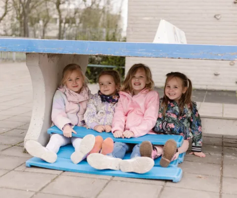 Kleine basisschool kinderen buiten onder een ping pong tafel